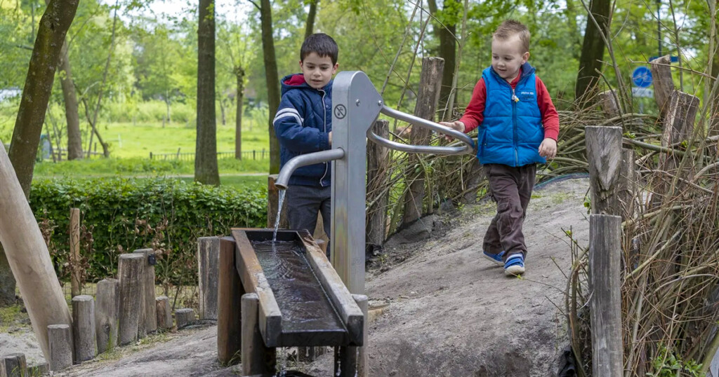 Textiel eruit, groen erin - kinderen bij waterpomp met waterloop