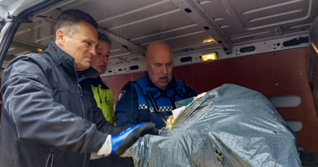 Drie mannen in een busje die de inhoud van een grijze vuilniszak controleren, v.l.n.r. wethouder Robin Heij, een medewerker van de RAD en een handhaver van de gemeente.