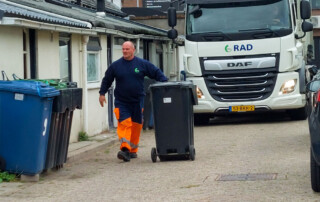 belader van de RAD loopt voor het inzamelvoertuig uit om Kliko's goed neer te zetten.