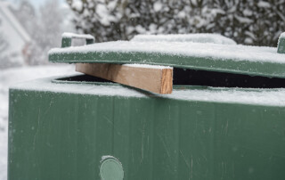 balkje hout tussen klep en gft-container in de winter