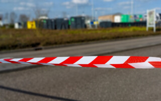 roodwit afzetlint, onscherp op de achtergrond de milieustraat in Westmaas
