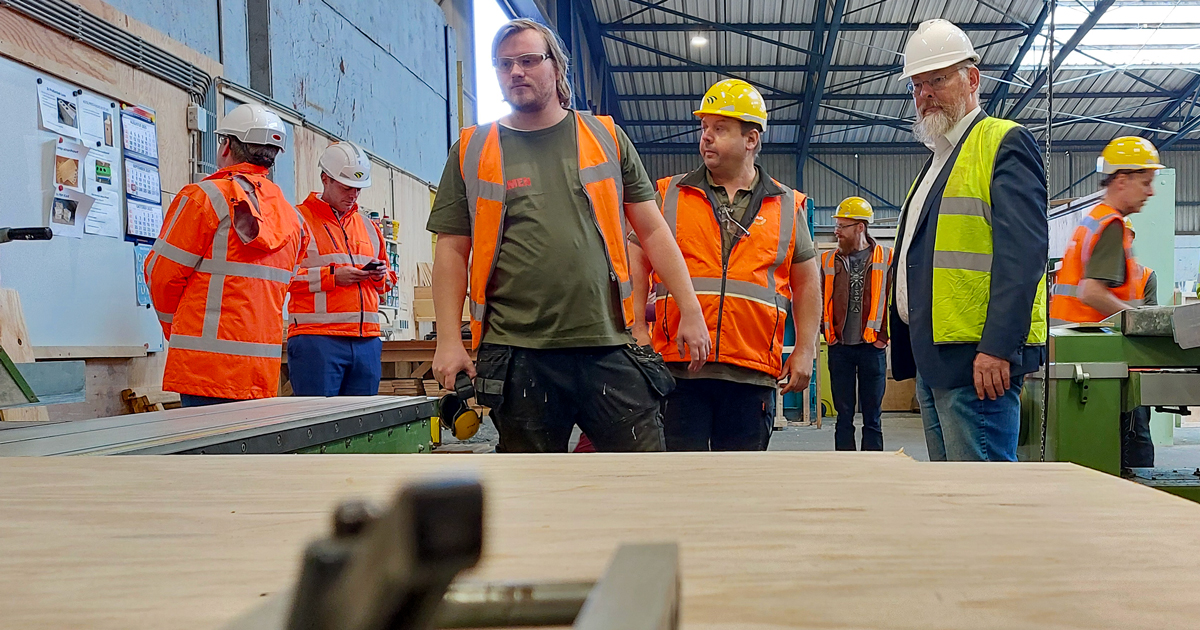 medewerkers circulaire houtwerkplaats en wethouder Huibert Steen bij zaagtafel