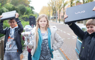 Basisschoolleerlingen met elektrische apparaten tijdens de E-waste Race